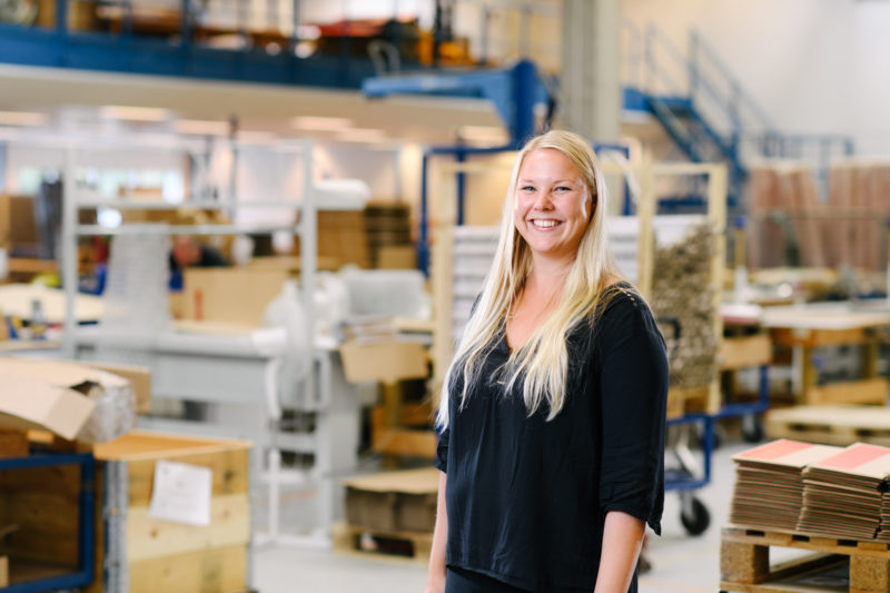 Bilden visar Emelie Blomqvist, en av våra medarbetare på ÅJ Distribution, i vår produktionshall för logistik av marknadsmaterial för säljorganisationer och kedjeföretag inom Retail.